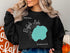 Black sweatshirt with "Beautiful Buffalo Lake Minnesota" graphic and compass rose.
