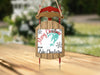 Red and wood Christmas ornament in the shape of a sled with text.