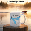 White mug with Lake Cuyamaca California design and compass on a lake background.