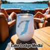 A white stemless wine tumbler rests on a wooden table aboard a boat with two women seated in the background.