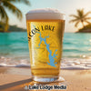 Pint glass with Falcon Lake graphic on a beach with palm trees.