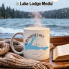 White mug with Grenada Lake map and compass design on a rainy window background.