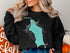Black sweatshirt with teal Jordan Pond map and compass graphic.