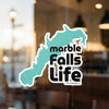 Teal outline sticker on window with text "Marble Falls Life" and copyright.