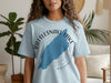 Light blue t-shirt with map of Rattlesnake Lake, Washington and compass graphic.