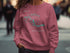 Pink sweatshirt with "Lake Sakakawea North Dakota" and compass rose graphic.