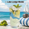 A tall glass of lemonade with a Lake Granby map design sits on a beachside table.