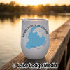 A white insulated wine tumbler featuring a blue map of Merrill Creek Reservoir and text sits on a wooden dock at sunset.