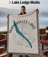 Man holding a throw blanket with Skaneateles Lake map and compass design.