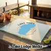 A rectangular glass cutting board with a blue Lake Tahoe graphic rests on an outdoor wooden table.