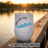A white insulated tumbler featuring a blue lake silhouette, compass graphic, and Dream Lake Colorado text, resting on a wooden dock.