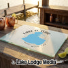 A glass cutting board featuring a blue map of Lake St. Clair rests on a wooden dock with drinks nearby.