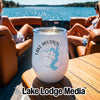 A white tumbler featuring a Lake Houston compass design sits on a wooden boat table.