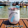 A white insulated tumbler featuring a Saratoga Lake design rests on a boat deck in front of a lake.
