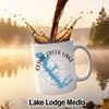 White mug with Cedar Creek Lake map and compass design, coffee pouring.
