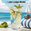 Tall glass with drink, limes, and mint, set against a beach scene with sailboat.