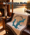 Tapestry throw with Lavon Lake map and compass design, placed on a leather couch.