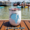 A white insulated travel tumbler with a Sebago Lake Maine map graphic sits on a wooden surface with a lake and people in the background.