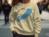 Light yellow sweatshirt with blue Sand Lake Ontario map and compass graphic.
