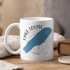 White mug with Lake Louise silhouette, compass, and text.