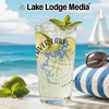 Glass with "Beaver Lake" and compass design on a beach with a sailboat.