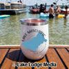A white insulated wine tumbler with a Lake Mascuppic New Hampshire graphic sits on a wooden boat deck with people swimming in the background.