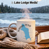 White mug with "Jordan Pond Maine" graphic steaming next to a book and scarf.