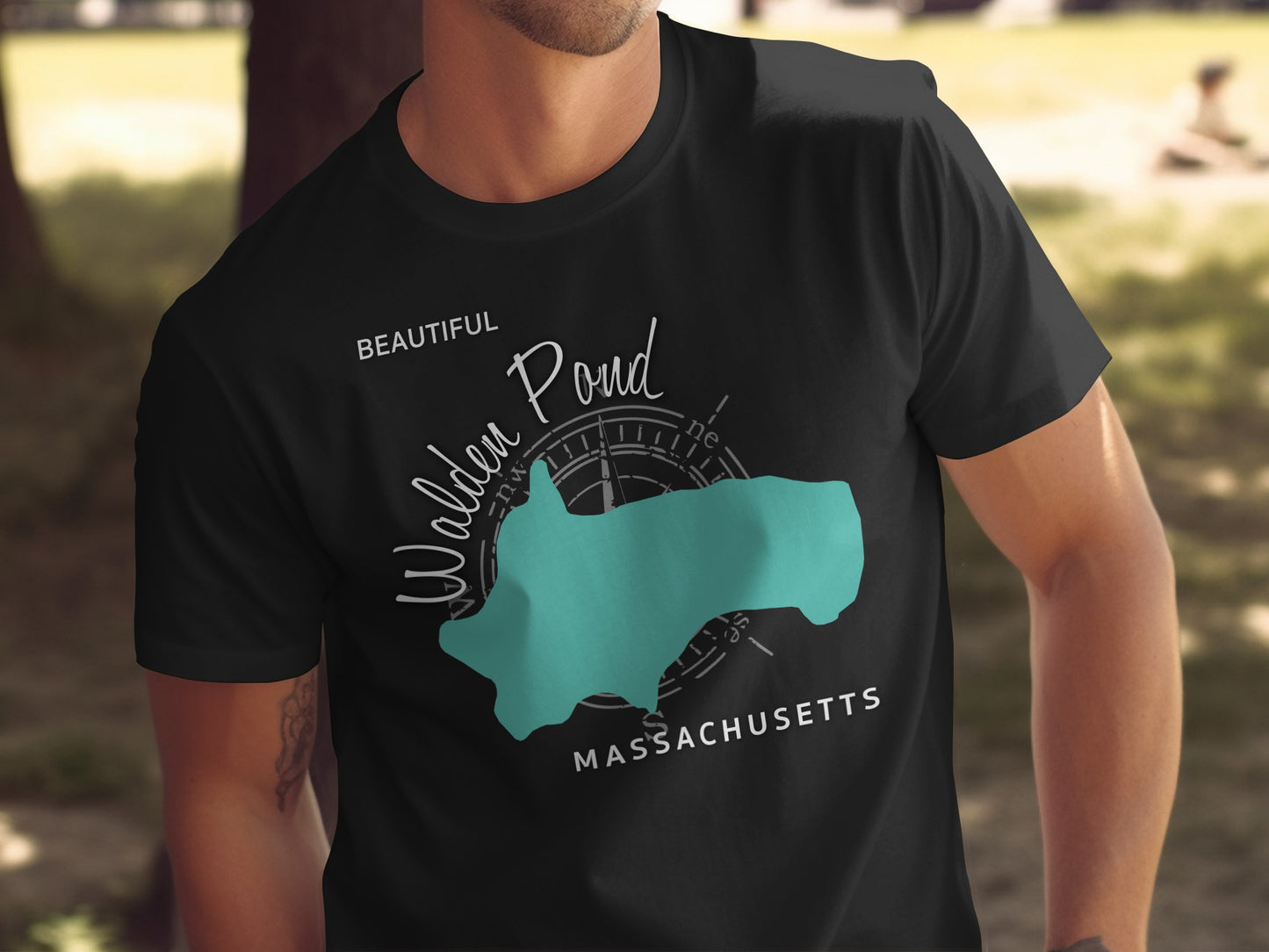 Black t-shirt featuring a teal outline of Walden Pond with "Beautiful Walden Pond Massachusetts" text.