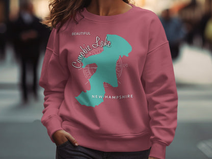 Pink sweatshirt featuring a teal map outline of the
"Beautiful Lake" and "New Hampshire".
