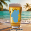 Beer glass with Lake Tahoe outline and compass rose on a beach.