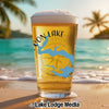 Beer glass with "Moon Lake Illinois" map and compass design on a beach.