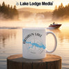 White mug with Rathbun Lake Iowa map and compass design on a wooden post.