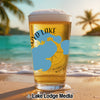 Glass of beer with "Lloyd Lake" and blue shapes on a beach with ocean waves.