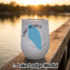 A white stemless wine tumbler with Lake Mohave, Nevada printed in blue rests on a wooden dock at sunset.