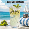 Glass with "Cherokee Lake" and compass design, garnished with lime and mint, by the ocean.