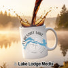 White mug with "Flagstaff Lake Maine" and compass design, coffee splashing.
