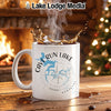 White mug with Cave Run Lake map and compass design, steaming coffee splashing.