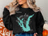 Black sweatshirt with "Calaveras Lake TEXAS" and compass rose graphic.