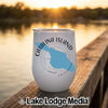 A white travel tumbler with a blue map of Catalina Island resting on a wooden dock at sunset.