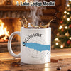 White mug with Oneida Lake map and compass design, steaming coffee, by fireplace.