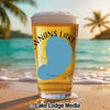 Beer glass with "Wnans Lake" text on a beach with palm trees and ocean.