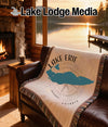 Cream blanket with Lake Erie map and compass design draped on leather couch.