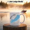 White mug with Sand Lake Ontario map and compass, steaming on wooden post by lake.