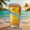 Glass of beer with "Miss's Lake" and California map design on a beach.