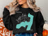 Black sweatshirt featuring a turquoise outline of a lake with a compass and "Beautiful Lake New York".