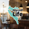 Turquoise outline decal with black text "Merced Life" on glass.