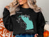 Black sweatshirt with a teal map outline of Lake Lawtonka, Oklahoma.