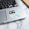 Sinclair Life sticker on a laptop keyboard featuring a turquoise lake outline.