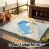 A glass cutting board featuring a blue map of Sandhill Lake, Wisconsin, rests on a wooden dock.