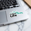 DeGray Life sticker with teal trees on a laptop.